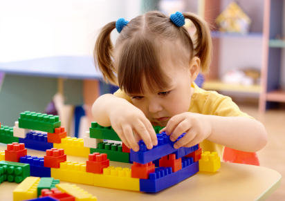 Little girl play with building bricks in preschool