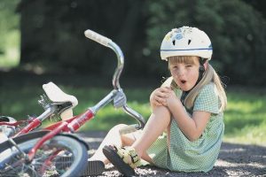 Girl with skinned knee from bike accident
