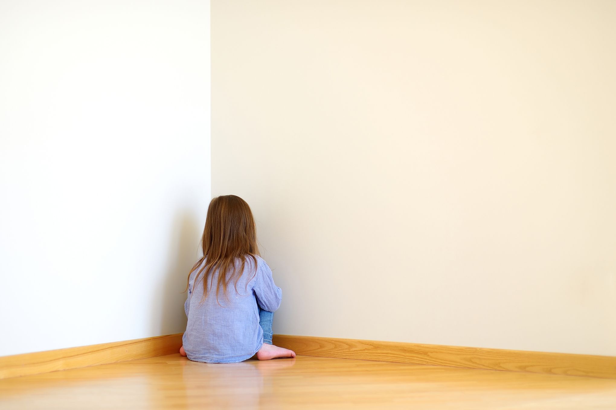 Very sad little girl sitting on a floor at home