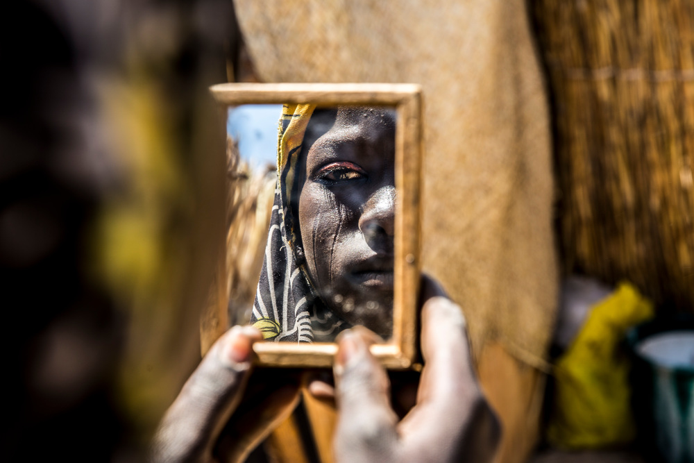  Νιγηρία: Στην επαρχία Ντίφα του νοτιοανατολικού Νίγηρα, που μαστίζεται από  τη βία της Μπόκο Χαράμ, μια γυναίκα κοιτάζεται στον καθρέφτη. Το βλέμμα της γεμάτο απόγνωση. Έφτασε στην κλινική των Γιατρών Χωρίς Σύνορα για προγεννετική φροντίδα. Ο σύζυγός της λαμβάνει φροντίδα ψυχικής υγείας. (Φεβρουάριος 2017).